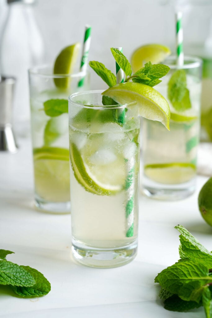 Tall glasses of mojitos with fresh lime slices, mint sprigs, and ice, ready to serve