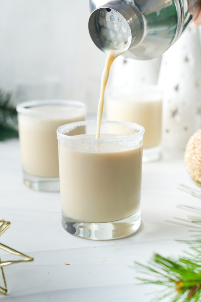 easy eggnog cocktail being poured from shaker into glass