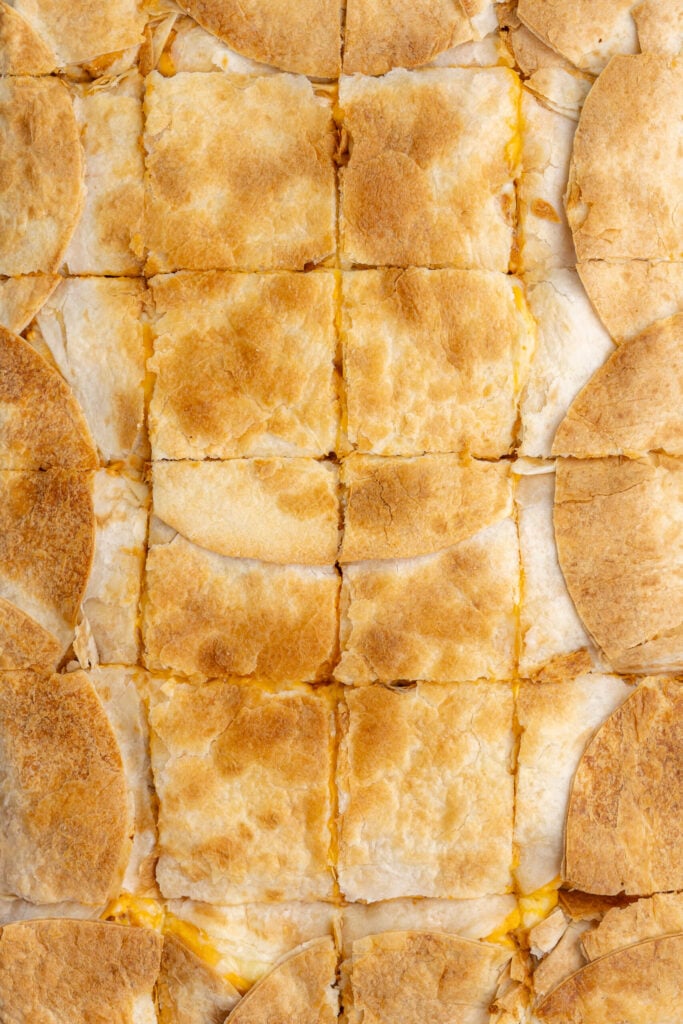 Golden, crispy sheet pan chicken quesadillas sliced into squares, ready to serve