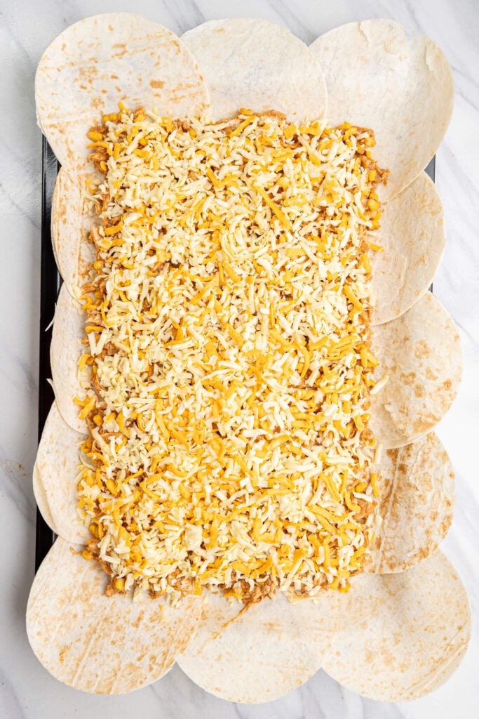 Cheese layer assembled ontop of chicken mixture and flour tortillas