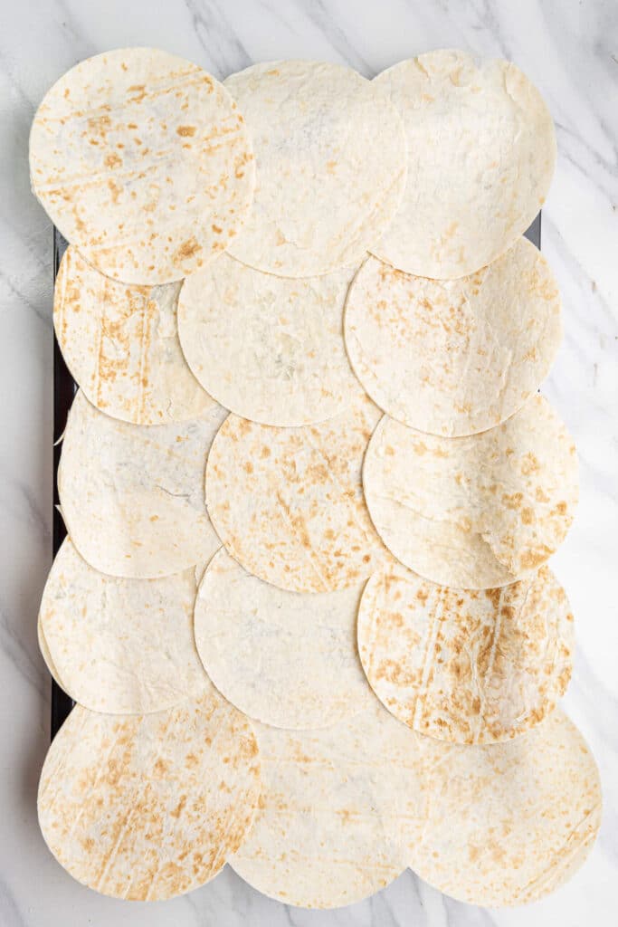 Flour tortillas arranged on a sheet pan, overlapping to form the base