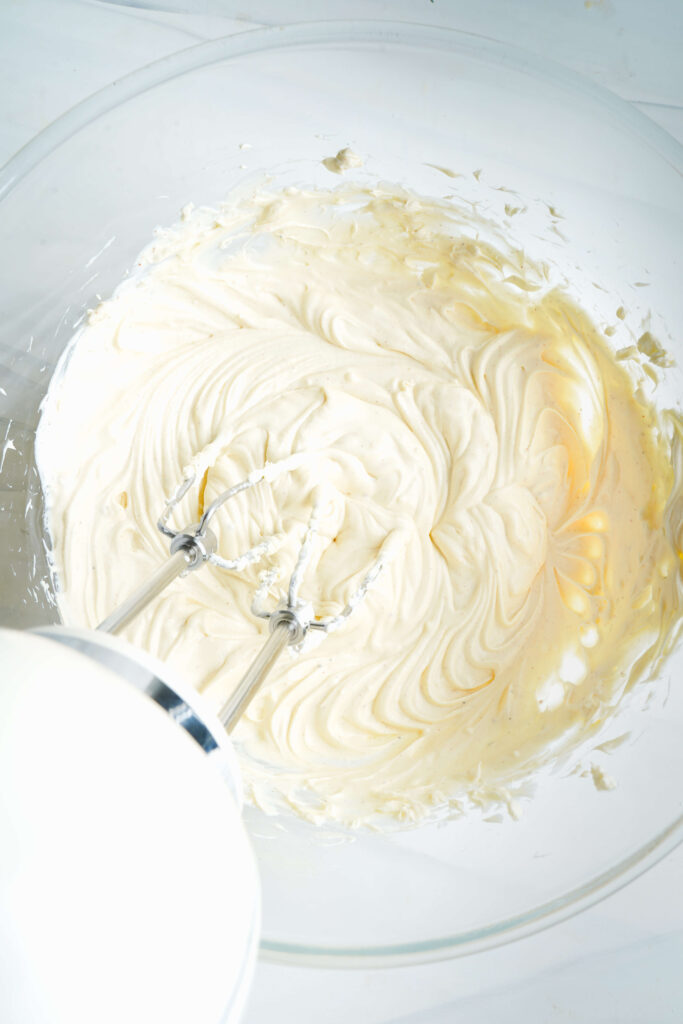 Smooth and creamy cream cheese mixture in a bowl after blending, forming the base for spinach artichoke dip.