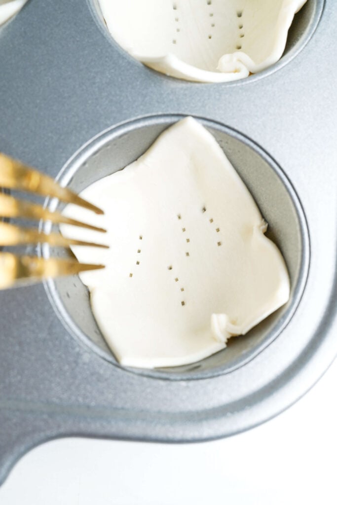 Puff pastry pressed into a muffin cup with small fork holes poked in the bottom to prevent over-puffing.