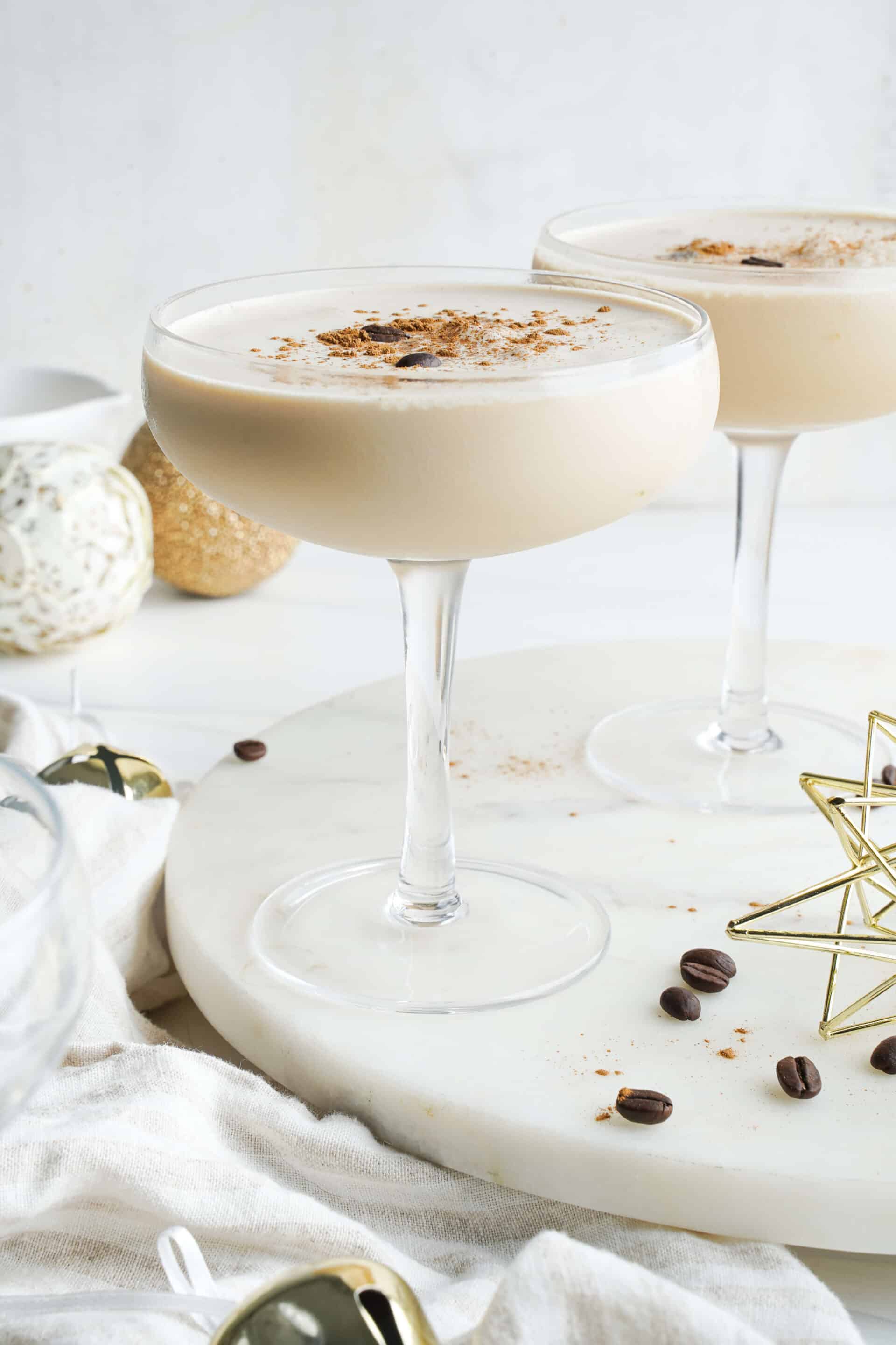 Eggnog espresso martini made with espresso, eggnog, spiced rum, and coffee liqueur, served in coupe glasses with a cinnamon garnish