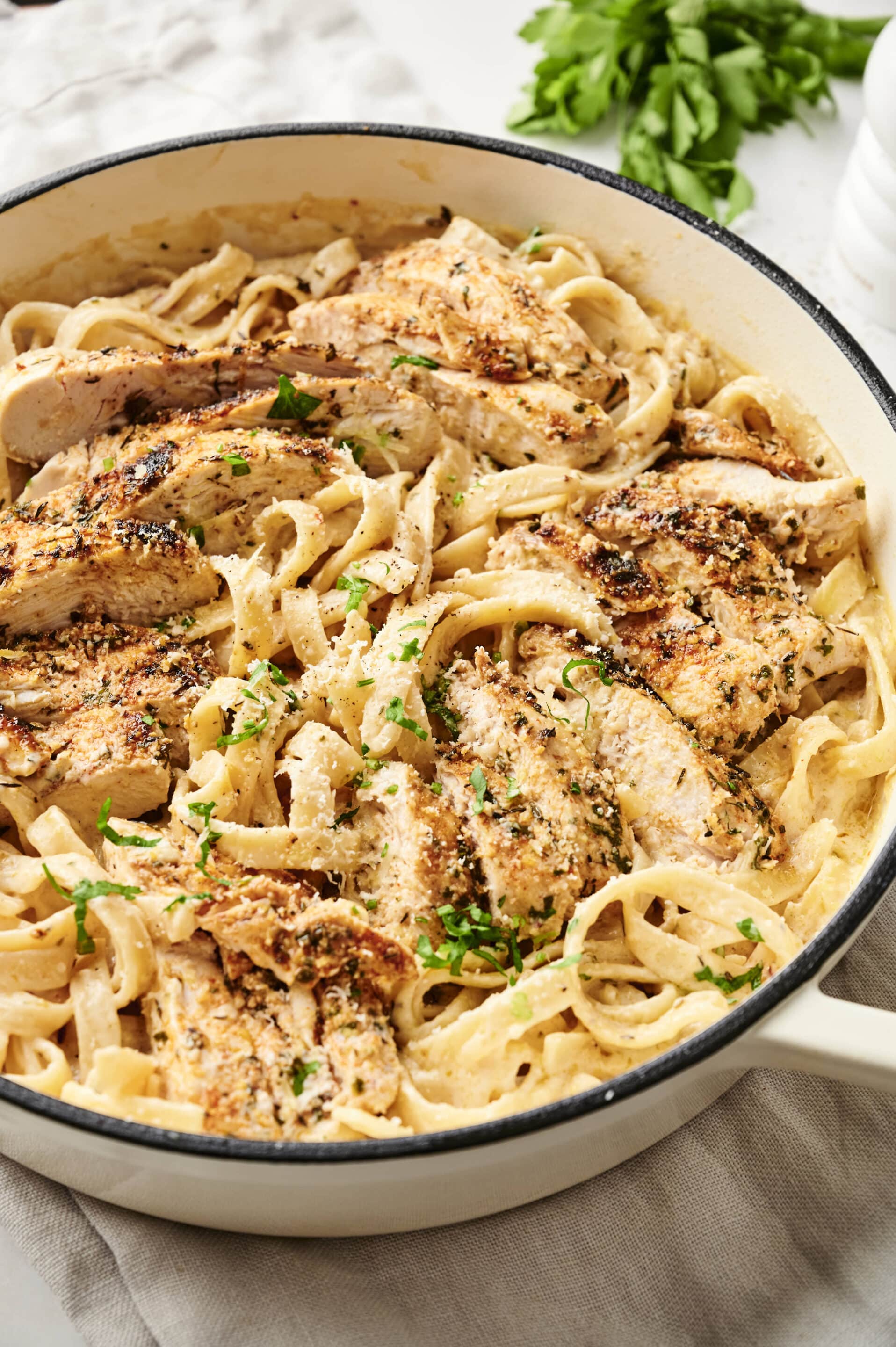 Garlic parmesan chicken and pasta with sliced seasoned chicken over creamy fettuccine in a skillet.