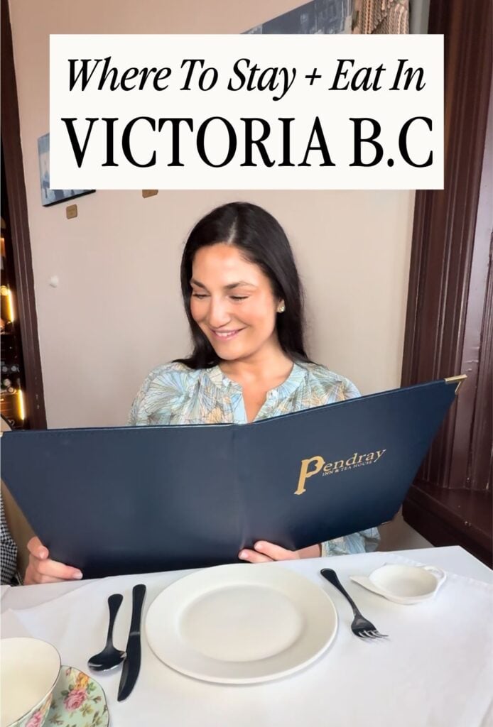Woman seated at a restaurant table holding an open menu with a title overlay reading โWhere To Stay + Eat In Victoria B.C.โ