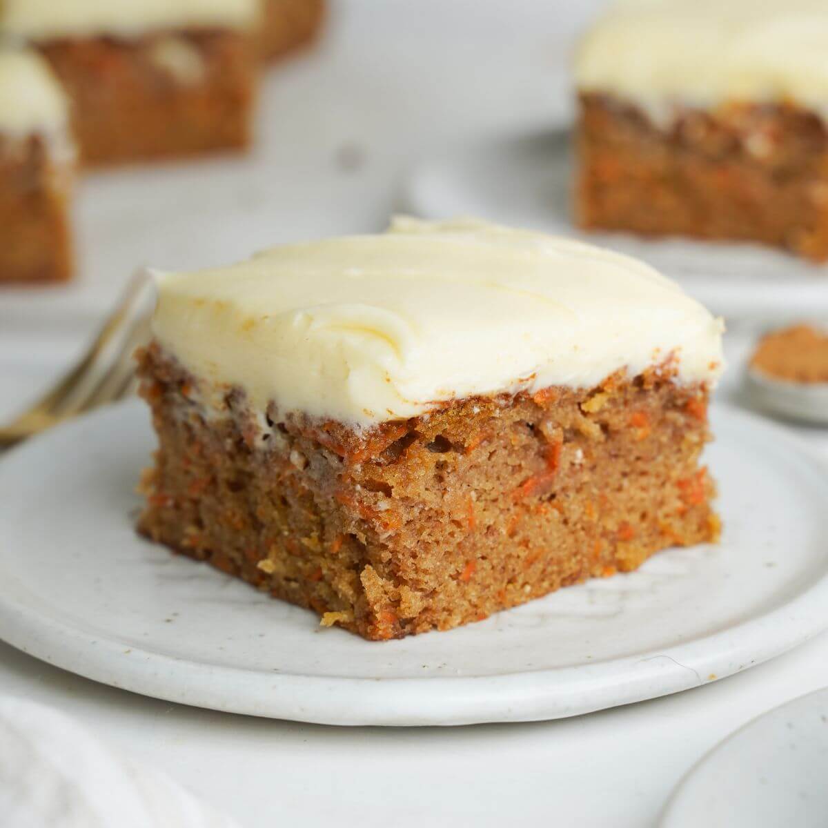 A slice of easy carrot cake with cream cheese frosting on a white plate