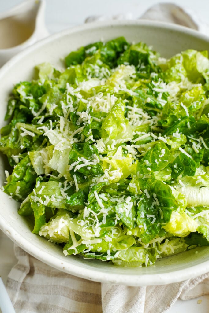 Close-up of chopped romaine lettuce topped with finely grated Parmesan cheese in a white bowl